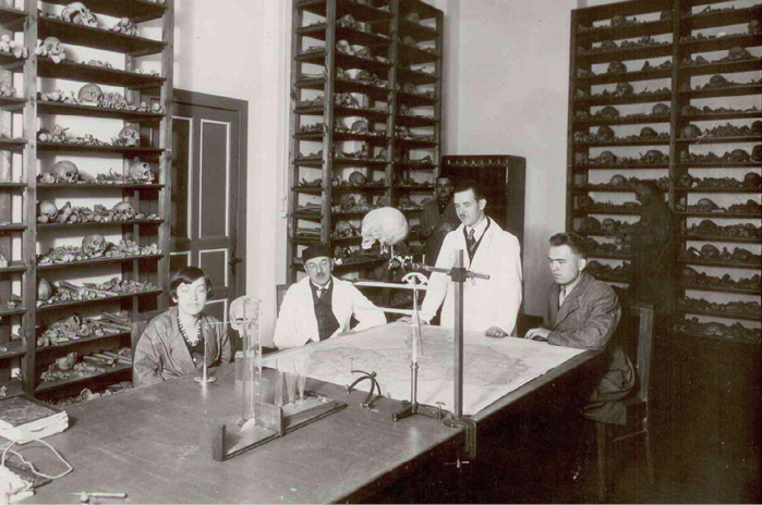 A 1935 photograph showing Adam Wrzosek, second from the left, and Michał Ćwirko-Godycki, second from the right, standing with volunteer assistants from the University of Poznań’s Department of Anthropology. They are gathered inside the osteological collection housed in the Marcinkowski Collegium in the Wilda district. 