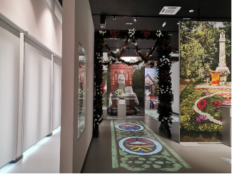 Sala procesji: na posadzce projekcje historycznych kwietnych dywanów, wokół fotografie udekorowanych stacji 