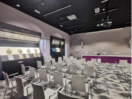 Sala archeologiczna: gabloty z monetami i artefaktami oraz przestrzeń konferencyjna z ekranem projekcyjnym