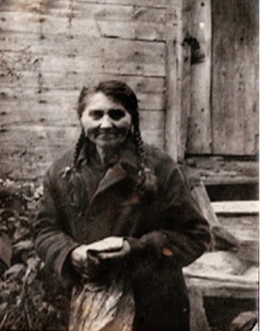 Pracownica gospodarstwa Cybulskich stoi przed lamusem, zdjęcie z okresu lat 40. XX wieku, ostatnia lokatorka zrujnowanego domu. 