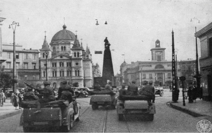 Plac Wolności w Łodzi z czasów okupacji. Samochody z żołnierzami niemieckimi. Zdjęcie czarno-białe.