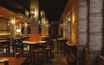 Przestronne wnętrze restauracji o nowoczesnym wystroju; przyciemnione światło.