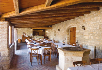 Taras restauracji w stylu rustykalnym; jasna, wapienna ściana z drewnianymi elementami.