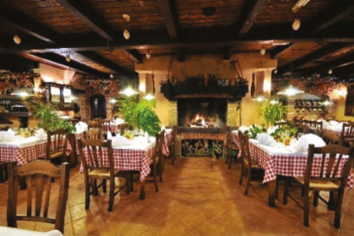 Wnętrze restauracji w stylu śródziemnomorskim. Stoliki nakryte obrusami w biało-czerwoną kratkę. 