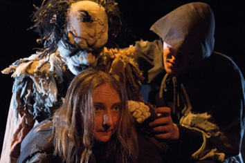 A woman with a wig and a man with a hoodie are standing in front of a man with a mask.