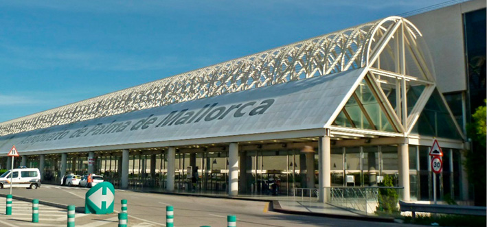 Outside departures at Palma airport, with the lettering “Aeropuerto de Palma de Mallorca” on the roof in large writing. 