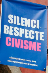 A banner hung between two buildings, above a pedestrian street. 