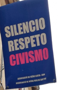 A banner hung between two buildings, above a pedestrian street. 