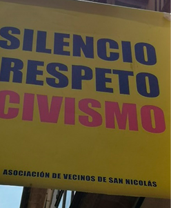 A banner hung between two buildings, above a pedestrian street. 