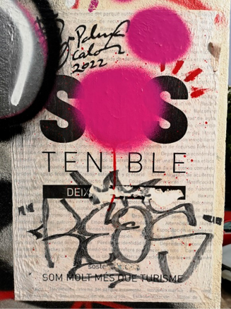 A poster on a wall, with pink dots spray-painted on top, and black tag graffiti written over the bottom half. 