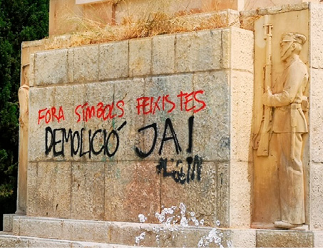 Graffiti in red and black spray paint on a stone wall at the base of the monument.  