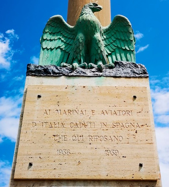 The base of a pillar, with a sculpture of an eagle above a stone plaque. 
