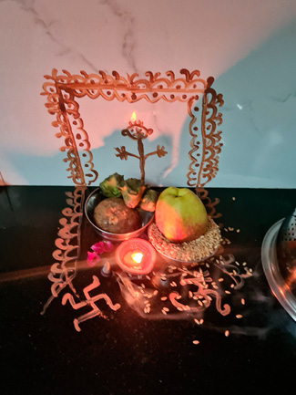 On the right, Lord Vishnu drawn from red ochre on a wall and surface, featuring a lit oil lamp, fruits, grains, and sacred symbols arranged neatly for Dev Uthan Ekadashi.
