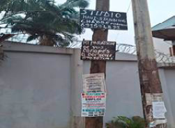 A photo showing two utility poles covered with seven stacked advertisements at Descente Victor Hugo, Yaoundé VI. 